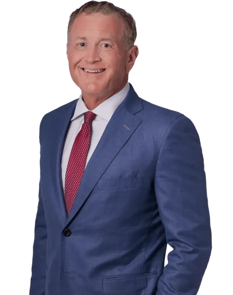 Professional middle-aged man wearing a blue suit, white shirt, and red patterned tie, smiling.