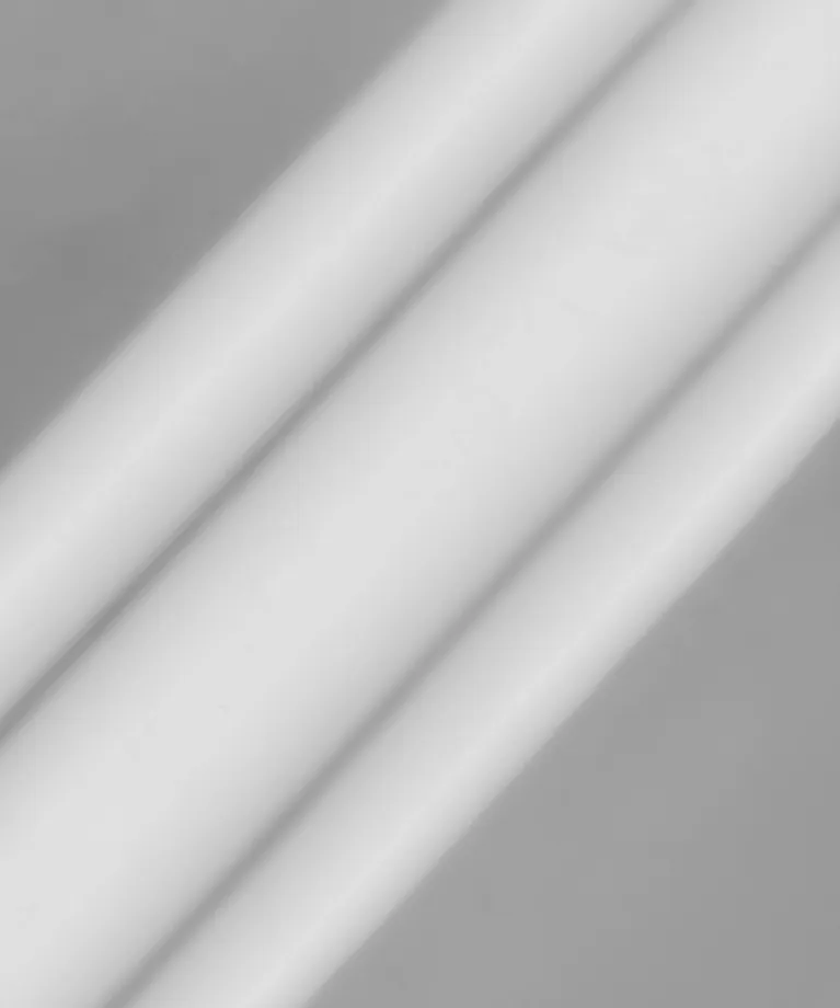 Close-up image of three parallel white cylindrical rods on a gray background.
